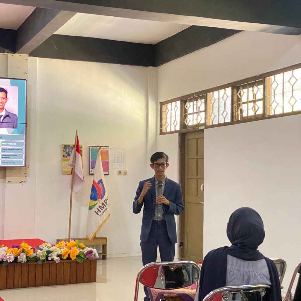 Pemateri workshop menjelaskan penggunaan software akuntansi Accurate kepada peserta dengan tampilan presentasi di layar proyektor.
